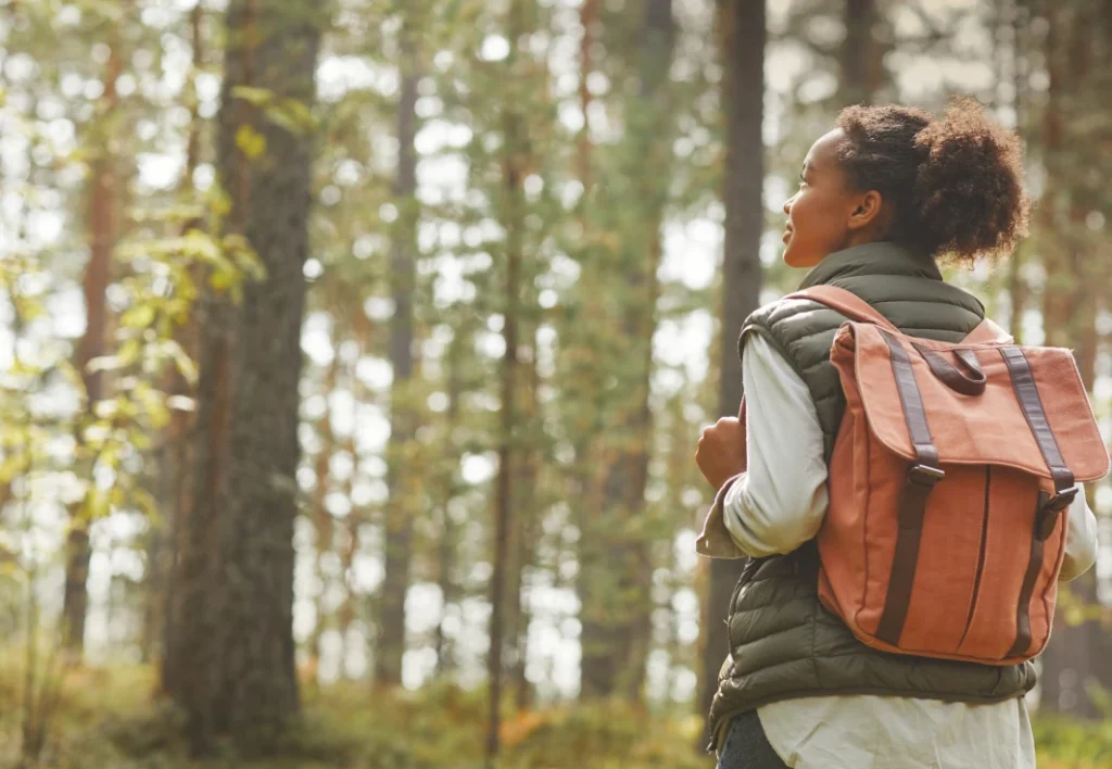 Young woman with an orange backpack in the forest