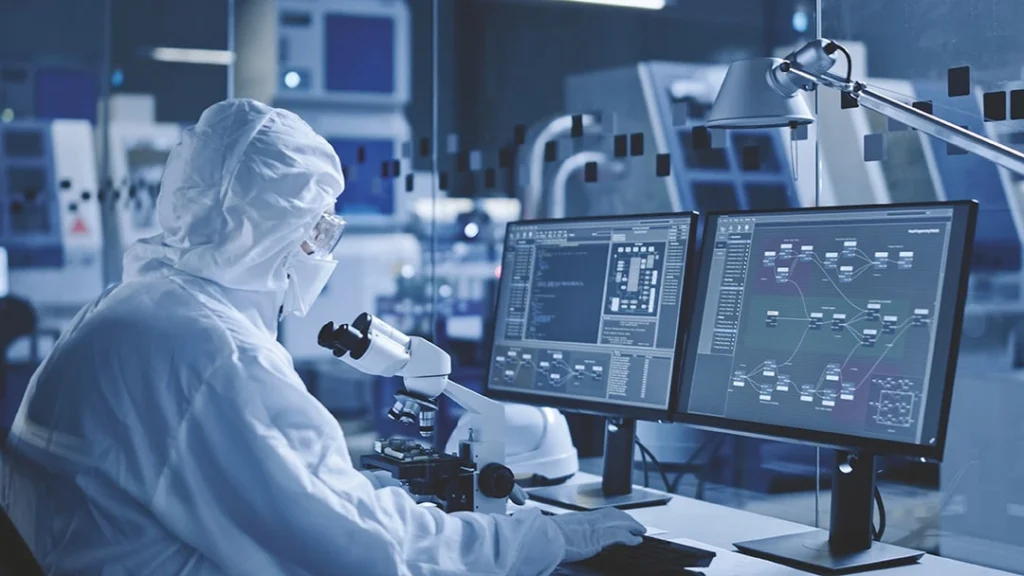 A man in a protective suit in front of a microscope in the laboratory