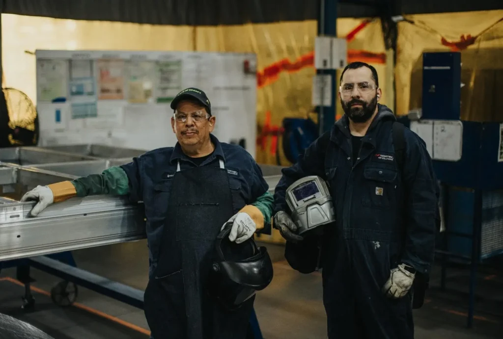 Two men with welding helmets in hand