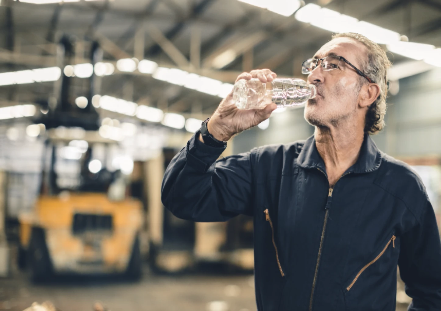 A man drinks water in a warehouse
