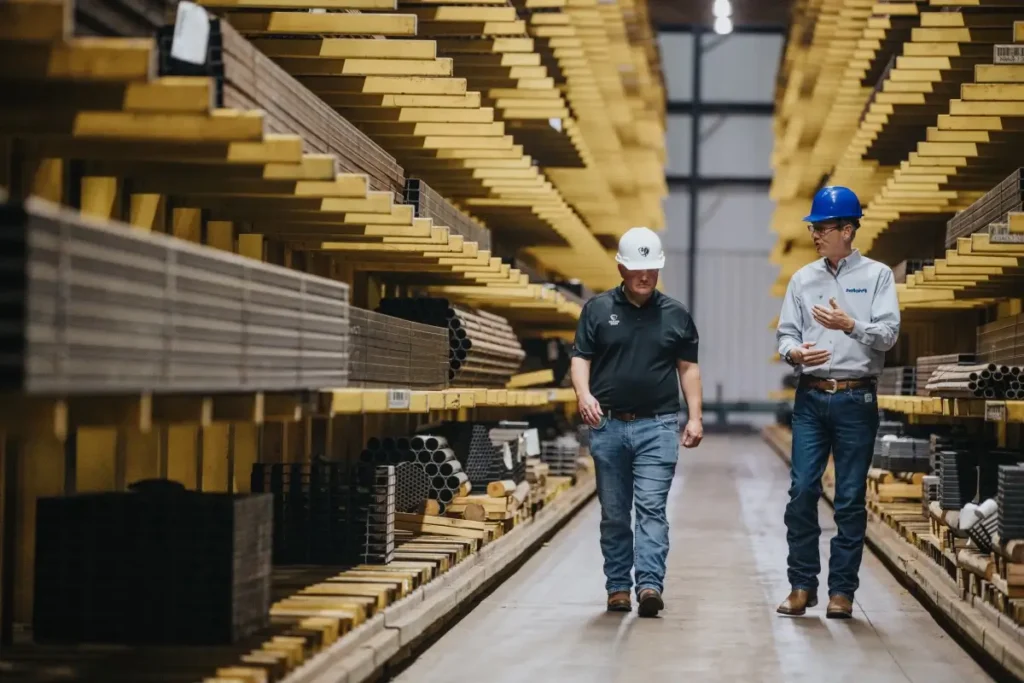 Two men wearing helmets walking through the warehouse