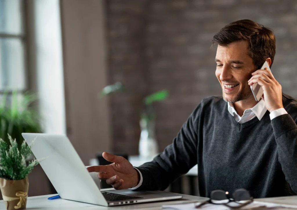 A man with a phone in his hand sitting at a desk